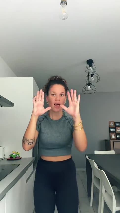 Bad Times AI example: a woman in a grey crop top lip-syncs and argues with the camera in her kitchen