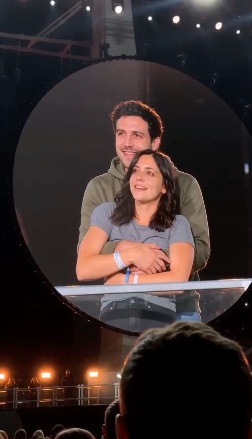 Coldplay Kiss Cam AI example: a couple on a concert big screen, one ducks out of frame and the other turns away