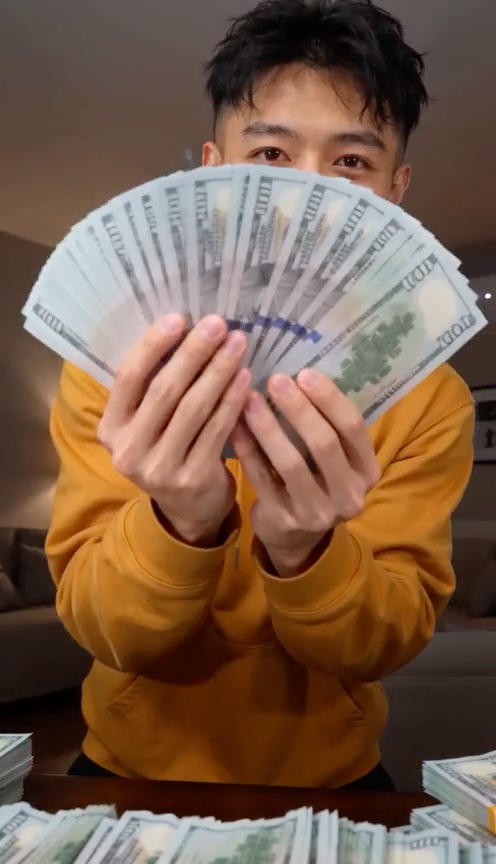 Money Flex AI example: a young man in a mustard hoodie fans a stack of banknotes at the camera